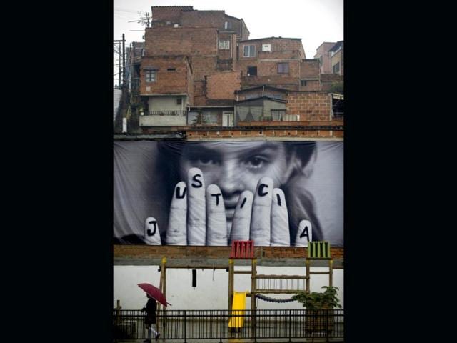 A girl walks past a giant photograph pasted on a wall at the Commune 1, a shantytown with one of the highest rates of urban violence in Medellin, Antioquia department, Colombia. AFP Photo/Raul Arboleda