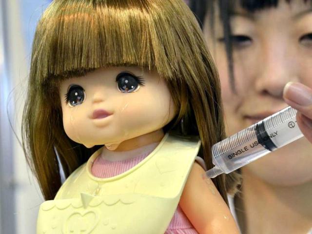 An employee of Japan's toy manufacturer Tomy shows off the company's new baby doll toy named Yume-chan, which cries when the user gives it an injection to the doll's arm, at a toy exhibition in Tokyo. Tomy will put the doll on the market in June. AFP