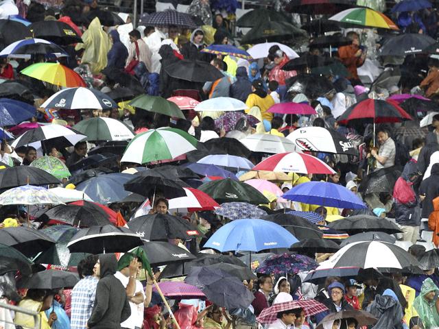 Fans hide under umbrellas as the rain pours down during the Twenty20 international cricket match between India and Australia in Sydney. AP Photo/Rob Griffith