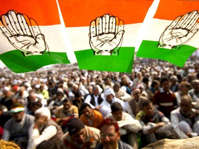 Spectators sit under a festoon of flags of the Congress party at an election rally in Meerut. AP Photo