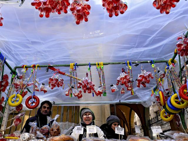 People protects thenself from the cold wind during Saint Blas Day, a day when people buy sweets blessed to protect their health, in Pamplona, northern Spain. (AP Photo/Alvaro Barrientos)