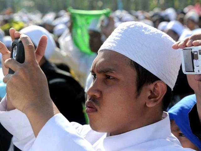 A man takes photos with his handphone during a ceremony to mark Milad-un-Nabi in Jakarta. AFP Photo/Adek Berry