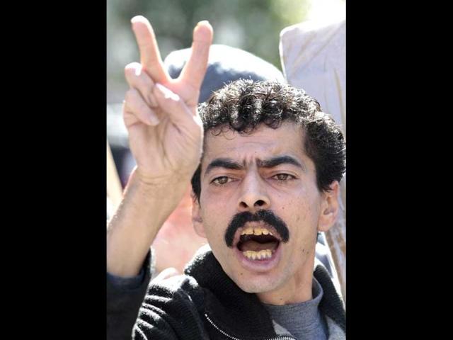 An anti-Syrian regime protester and supporter of the Islamic group Jamaa Islamiya, who are opposed to Syrian President Bashar Assad, flashes the victory sign as he shouts slogans during a demonstration where a number of Assad supporters were also protesting, in front the Russian embassy, in Beirut, Lebanon (AP Photo)