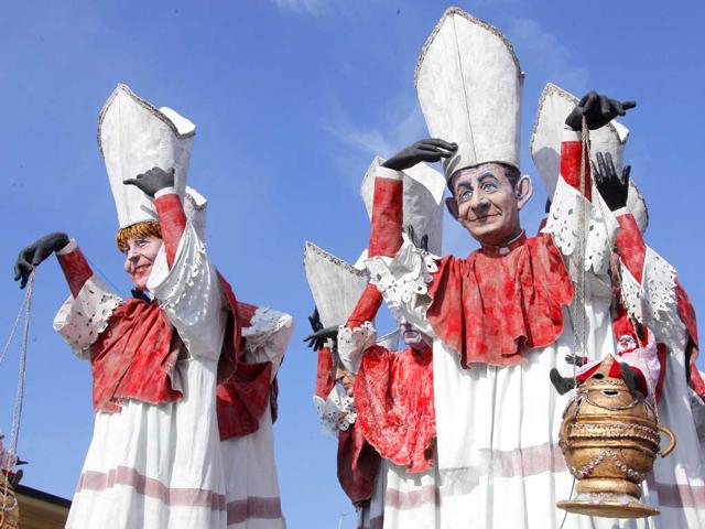 A carnival float showing US President Barack Obama, German Chancellor Angela Merkel (L), Italian prime minister Mario Monti and French President Nikolas Sarkozy (R) dressed as ecclesiastes parade during the carnival in Viareggio. AFP PHOTO/Fabio Muzzi