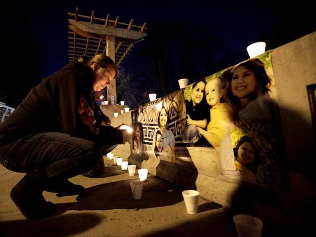 Theresa Vanderhoff lights a candle next to photographs of Susan Cox Powell and her sons Braden and Charlie, during a candlelight vigil at McKinley Park in Tacoma, Wash. the day after Braden and Charlie Powell were killed along with their father, Josh Powell, when police said Josh Powell set fire to the house they were in on Sunday. Susan Powell went mysteriously missing from their West Valley City, Utah, home in December 2009. AP