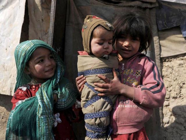 An internally displaced Afghan girl from Helmand province holds her brother as she and another girl stand outside a mud shelter for the displaced at the Charhi Qambar refugee camp on the outskirts of Kabul. Fleeing NATO bombardment and Taliban intimidation, thousands of Afghans in refugee camps in the capital Kabul face a new enemy: an unusually bitter winter that is killing their children. AFP Photo/ Shah Marai