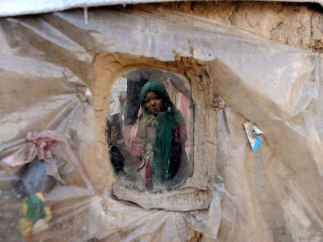 An internally displaced Afghan girl from Helmand province outside a mud shelter for the displaced is reflected in the window as another girl looks out at the Charhi Qambar refugee camp on the outskirts of Kabul. Fleeing NATO bombardment and Taliban intimidation, thousands of Afghans in refugee camps in the capital Kabul face a new enemy: an unusually bitter winter that is killing their children. AFP Photo/ Shah Marai
