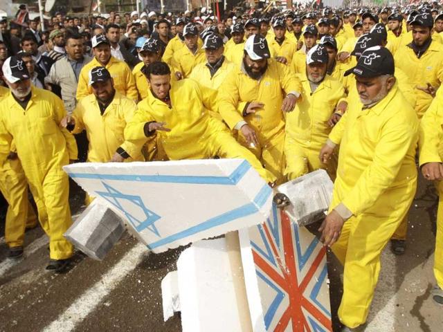Followers of Shiite cleric Muqtada al-Sadr smash symbolic British and Israeli flags as they celebrate the US withdrawal in the Shiite stronghold of Sadr City in Baghdad. (AP Photo/Khalid Mohammed)