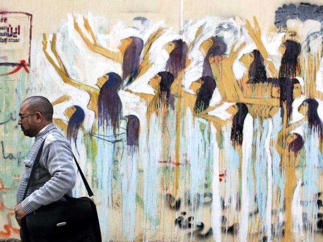 An Egyptian man passes a mural and graffiti in Arabic that reads "where is freedom and social justice?" in Cairo, Egypt. AP Photo/Nasser Nasser