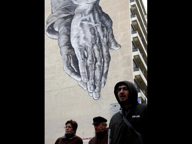 Demonstrators pass under a mural during protests against planned reforms by Greece's coalition government in Athens. REUTERS/John Kolesidis