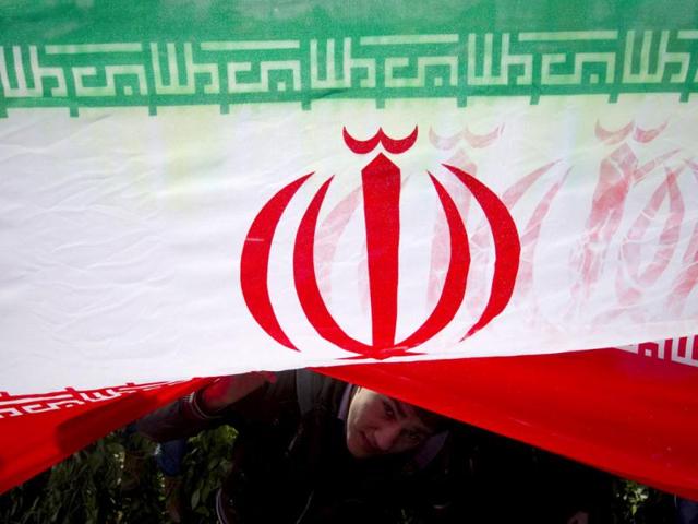 A demonstrator peeks from under an Iranian flag during a ceremony to mark the 33rd anniversary of the Islamic Revolution, in Tehran's Azadi square. Iran's President Mahmoud Ahmadinejad said on the anniversary of the revolution that the Islamic Republic would soon announce "very important" achievements in the nuclear field, state TV reported. Reuters/Caren Firouz