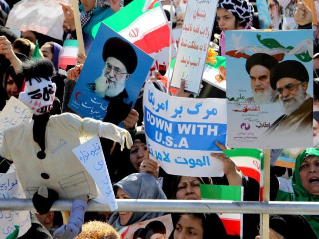 Iranian women hold anti-US slogans and portraits of supreme leader, Ayatollah Ali khamenei during a rally to mark the 33rd anniversary of the Islamic revolution in Azadi (Freedom) square in Tehran. Iranian President Mahmoud Ahmadinejad said that Iran has broken the "idol" of the Holocaust underpinning the creation of the Israeli state and US hegemony. AFP Photo/Atta Kenare