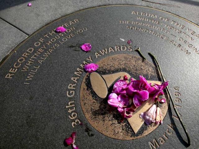 Flowers placed on a Grammy sidewalk plaque honoring Whitney Houston's wins for Record of the Year and Album of the Year in 36th Grammy Awards, have been scattered and replaced several times outside the Grammy Museum in Los Angeles. Houston died on the eve of the 54th Grammys, at the Beverly Hilton Hotel, where she was preparing to attend a pre-Grammy party. She was 48. (AP Photo)