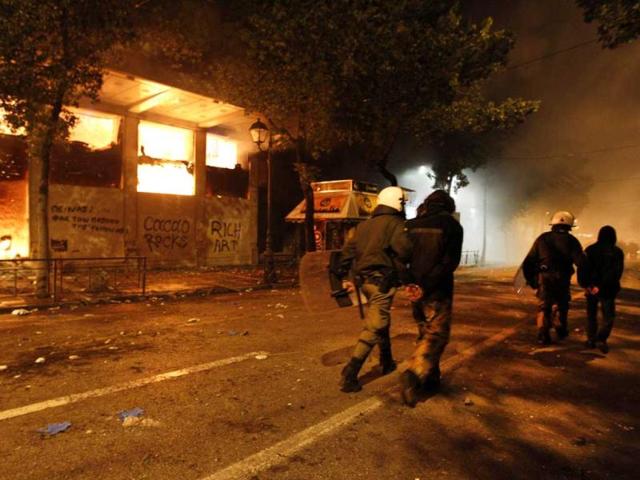 Riot police move detained protesters past a burning historic building during violent protests in central Athens. Historic cinemas, cafes and shops went up in flames in central Athens on Sunday as black-masked protesters fought Greek police outside parliament, while inside lawmakers looked set to defy the public rage by endorsing a new EU/IMF austerity deal. (Reuters)