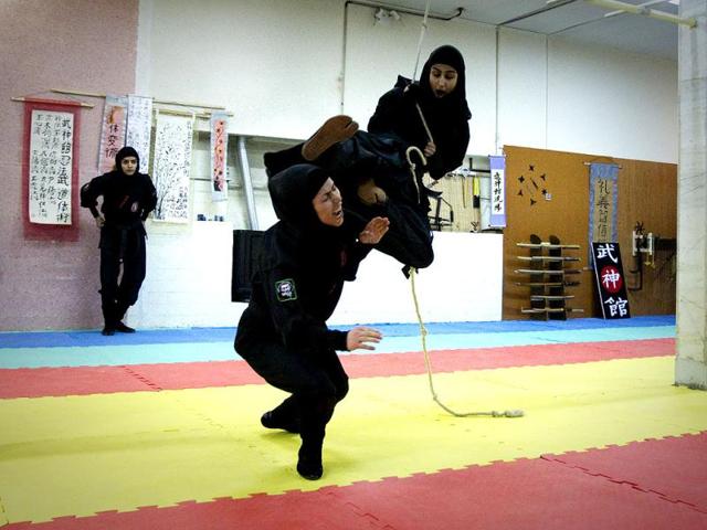 A Ninjutsu practitioner swings from a rope to attack as members of various Ninjutsu schools showcase their skills to the media in a gym at Karaj. (Reuters/Caren Firouz)