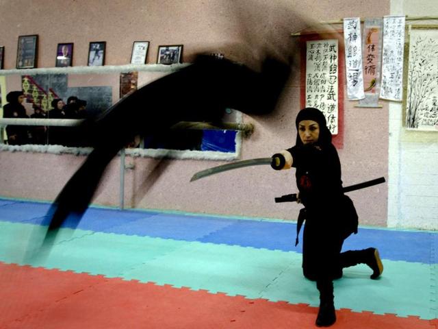A Ninjutsu practitioner jumps over a sword as members of various Ninjutsu schools showcase their skills to the media in their gym at Karaj. (Reuters/Caren Firouz)