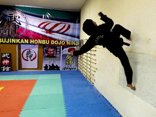 A Ninjutsu practitioner runs up a wall as members of various Ninjutsu schools showcase their skills to the media in a gym at Karaj. (Reuters/Caren Firouz)