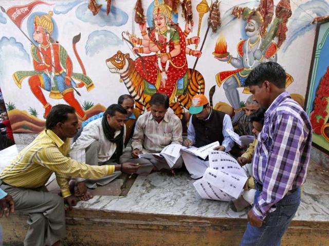 Voters look at electoral lists to check their names outside a polling booth in Varanasi. AP Photo/Rajesh Kumar Singh