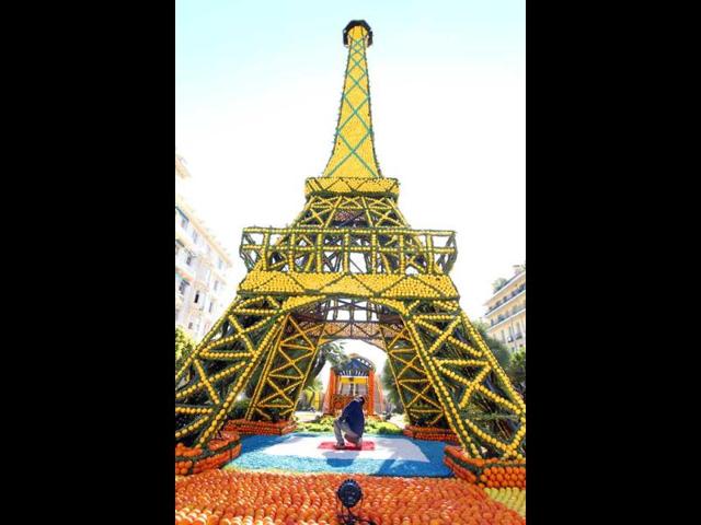 A man works on a sculpture made with oranges and lemons representing the Eiffel tower in Menton on the French Riviera, ahead of the start of the "Fete du Citron" (lemon carnival). AFP/Valery Hache