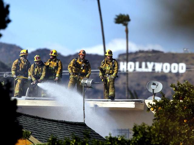 Firefighters battle a blaze at a house where authorities say at least three people were shot and wounded in east Los Angeles. AP/Patrick T. Fallon