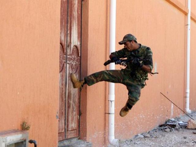 A fighter loyal to Libya's new regime the Transitional national Council (NTC) tries to break down a door during fighting in the town of Sirte, as the fighters move in for the kill against Muammar Gaddafi's diehards in his hometown. AFP/Ahmad Al-Rubaye, File