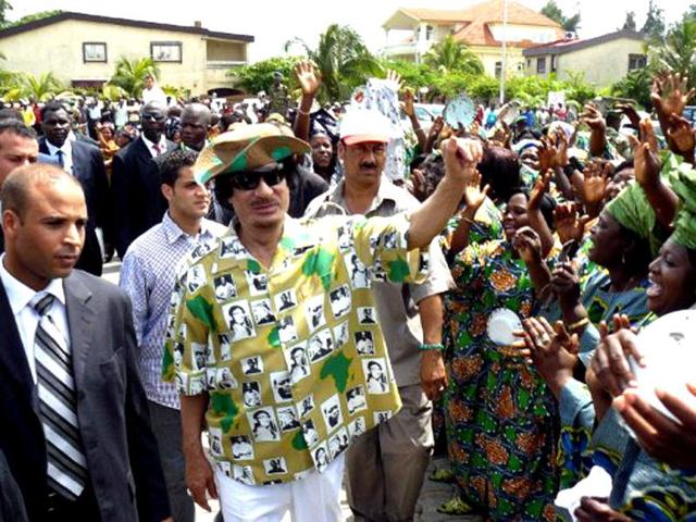 Libyan leader Muammar Gaddafi (C) waves to the cheering crowd on his way to inaugurate the construction of 55 villas, bankrolled by Libya built on the waterfront in Cotonou, Benin. AFP/Fiacre Vidjingninou, File