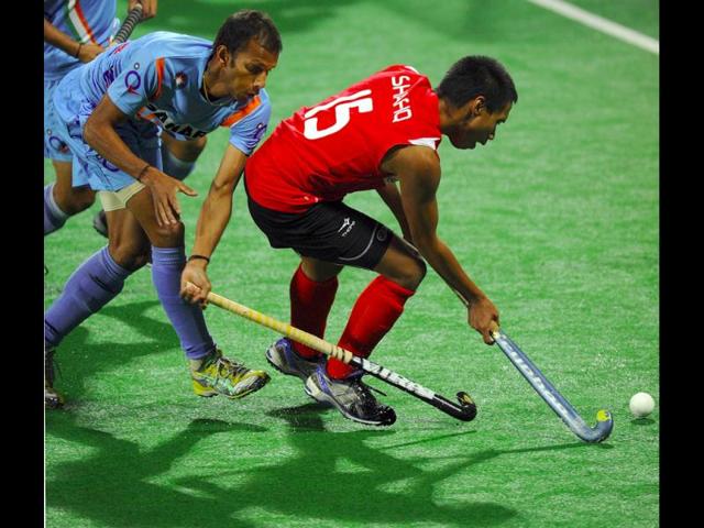 Sunil Sowmarpet Vitalacharya of India (L) blocks Muhammad Shafiq of Singapore during the men's field hockey match of the FIH London 2012 Olympic Hockey qualifying tournament at the Major Dhyan Chand National Stadium in New Delhi. AFP/Prakash Singh
