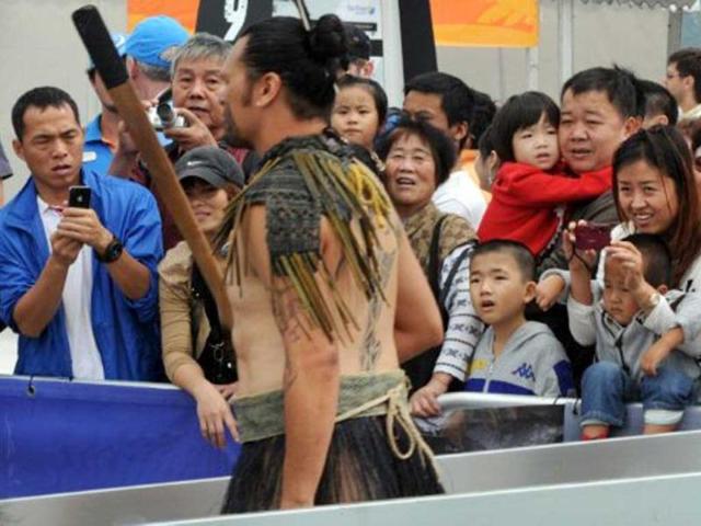 Chinese yachting fans react as a Maori warrior walks to the Camper/Team New Zealand boat before the In-Port-Race which was eventually won by Spain's Team Telefonica on the eve of the Volvo Ocean Race departure from Sanya, Hainan Island. AFP Photo/Mark Ralston