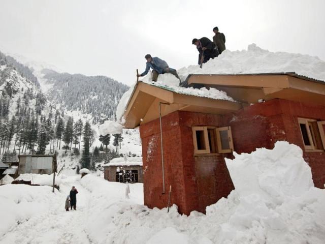 Kashmiri boys clear snow from the roof of a house in Gagangeri, some 80 kilometers (50 miles) northeast of Srinagar. Heavy snowfall across Kashmir valley has prompted authorities to issue an avalanche warning for most areas lying close to the mountains, according to a news agency. Avalanches and landslides are common in the disputed Himalayan region. AP Photo/ Dar Yasin