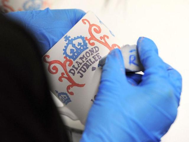 A worker paints diamond jubilee mugs at the Emma Bridgewater pottery in Hanley, Stoke on Trent, England as part of a collection to celebrate the queen’s 60-year reign. The Diamond Jubilee range will feature both hand decorated spongeware patterns and lithographed prints on celebratory mugs, bowls, plates, teapots and a ceramic crown emblazoned with the slogans ‘Sixty Years a Queen’ and ‘Steadfast and True. AFP PHOTO / Andrew Yates