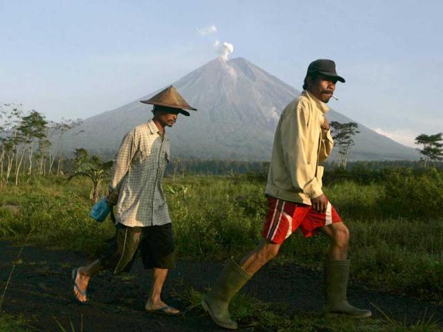 Local farmers walk by as Mount Semeru spews volcanic materials from its crater, in Lumajang, East Java. AP Photo/Trisnadi