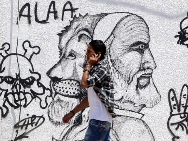 A Libyan man walks past a caricature of Muammar Gaddafi and Libyan resistance fighter Omar al-Mukhtar in Benghazi. (Reuters/Amr Abdallah Dalsh)