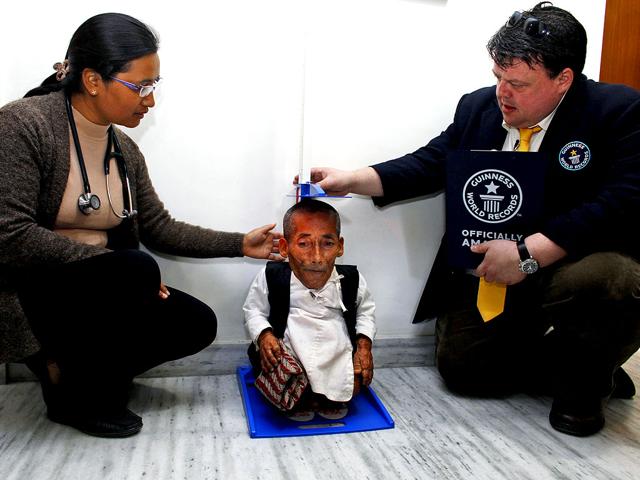 Editor in Chief of Guinness World Records Craig Glanday, right, and Dr. Kashila Pradhan, left, officially measure Nepal's Chandra Bahadur Dangi, 72, who says he's only 22 inches (56 centimeters) tall, at the CIWEC clinic in Katmandu, Nepal. (AP Photo/Niranjan Shrestha)