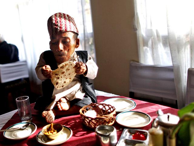 Nepal's Chandra Bahadur Dangi, 72, sits on a table during breakfast just hours before he was to be measured by officials, in Katmandu, Nepal. (AP Photo/Niranjan Shrestha)