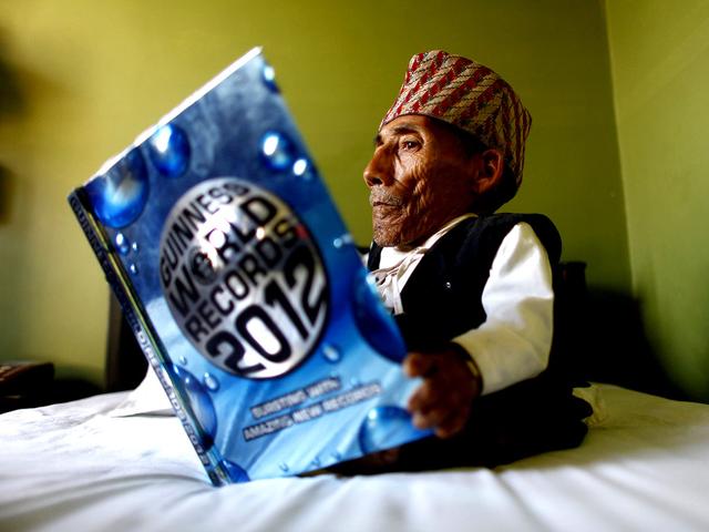 World's shortest man Chandra Bahadur Dangi, 72, only 21.5 inches (54.6 centimeters) tall, looks at a copy of the Guinness World Record book at a guesthouse just hours before he was to be measured by officials, in Katmandu, Nepal. Dangi snatched the title of the world's shortest man from Junrey Balawing of the Philippines, who is 23.5 inches (60 centimeters) tall. (AP Photo/Niranjan Shrestha)
