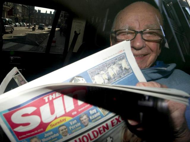 News Corporation Chief Rupert Murdoch holds up a copy of the newly launched 'The Sun on Sunday' newspaper as he leaves his London home. (AFP photo/Carl Court)