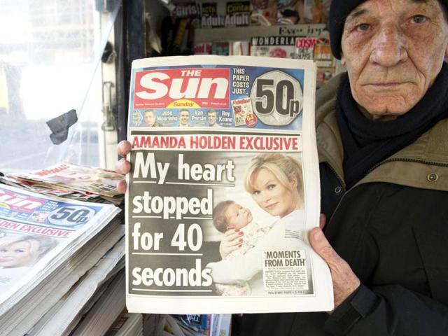 A person holds up Sunday's edition of the new British Newspaper 'The Sun on Sunday'. Rupert Murdoch's Sun on Sunday tabloid rolled off the presses for the first time, with a pledge that the paper replacing the scandal-hit News of the World would abide by ethical standards. (AFP photo/Miguel Medina)