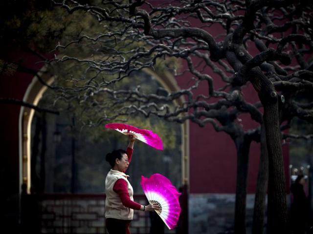 A Chinese woman performs morning exercise with fans at the Ditan park in Beijing, China. AP Photo/Andy Wong