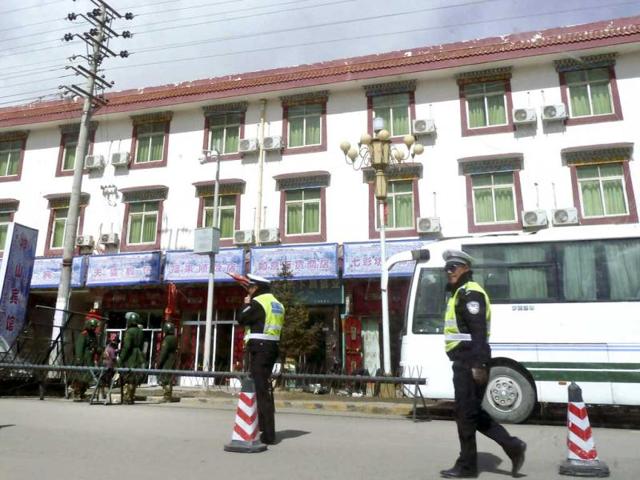 In-this-photo-Chinese-paramilitary-policemen-left-stand-guard-while-traffic-police-officers-control-traffic-near-barricades-set-up-along-the-main-street-of-Aba-county-seat-in-China-s-Sichuan-province-China-s-stifling-lockdown-of-this-Tibetan-monastery-town-has-not-only-been-about-patrolling-its-otherwise-sleepy-streets-Beijing-is-also-policing-the-minds-of-a-community-at-the-center-of-self-immolation-protests-against-Chinese-rule-AP-Photo-Gillian-Wong In-this-photo-Chinese-paramilitary-policemen-left-stand-guard-while-traffic-police-officers-control-traffic-near-barricades-set-up-along-the-main-street-of-Aba-county-seat-in-China-s-Sichuan-province-China-s-stifling-lockdown-of-this-Tibetan-monastery-town-has-not-only-been-about-patrolling-its-otherwise-sleepy-streets-Beijing-is-also-policing-the-minds-of-a-community-at-the-center-of-self-immolation-protests-against-Chinese-rule-AP-Photo-Gillian-Wong
