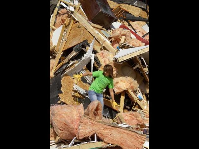 Brooke Hill helps a friend salvage and clean up what they can from her home in Harrisburg, Ill. A pre-dawn twister flattened entire blocks of homes Wednesday as violent storms ravaged the Midwest and South. (AP Photo/Seth Perlman)