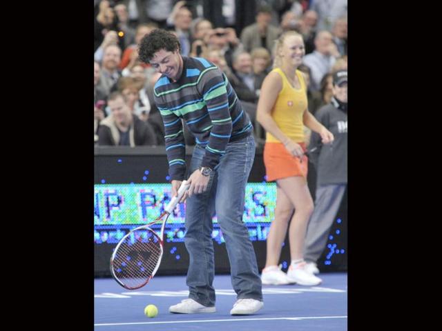 Golfer Rory Mcilroy, left, tees up a tennis ball to hit to Maria Sharapova as Caroline Wozniacki looks on in the BNP Paribas Showdown exhibition tennis match, at Madison Square Garden in New York. (AP Photo/Bill Kostroun)