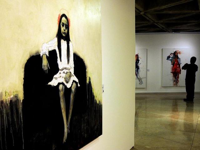 A visitor watches Elia Arce's series "Gulliver and the Pin-Up Girl", part of the exhibition by Costa Rican artists held at the National Gallery in San Jose. The exhibition is part of the "Museums and Galleries Route" during the XIII International Arts Festival to be held in San Jose from 1 to 25 March. (AFP Photo)