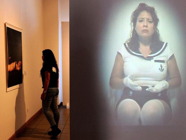 A visitor watches Elia Arce's series "Gulliver and the Pin-Up Girl", part of the exhibition by Costa Rican artists held at the National Gallery in San Jose on March 7, 2012. The exhibition is part of the "Museums and Galleries Route" during the XIII International Arts Festival to be held in San Jose from 1 to 25 March. (AFP Photo)