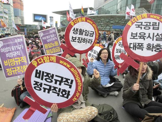 South Korean female workers shout slogans during a rally to mark International Women's Day in Seoul, South Korea. The letters read 'Preserve a living wage and hire more temporary employees'. AP/Ahn Young-joon