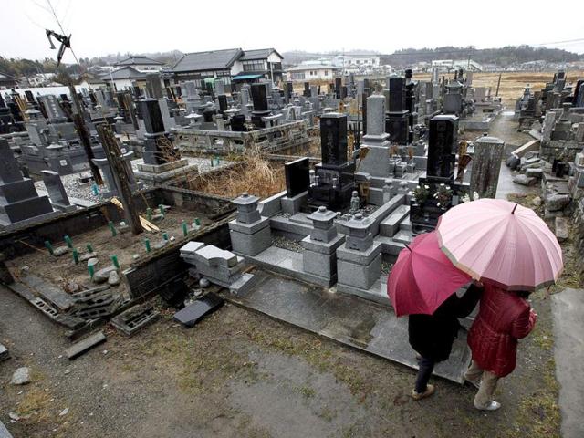 Taki Nemoto (R) and her family visit a damaged graveyard to pay respects to her mother who was killed during last year's earthquake and tsunami in Hirono town, Fukushima prefecture. (Reuters/Kim Kyung-Hoon)