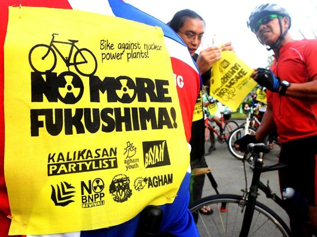 Filipino environmetal activists place slogans on bikers as they hold a bike and run event to mark the anniversary of the Fukushima nuclear meltdown catastrophe in Quezon City suburban Manila. (AFP photo/ Jay Directo)