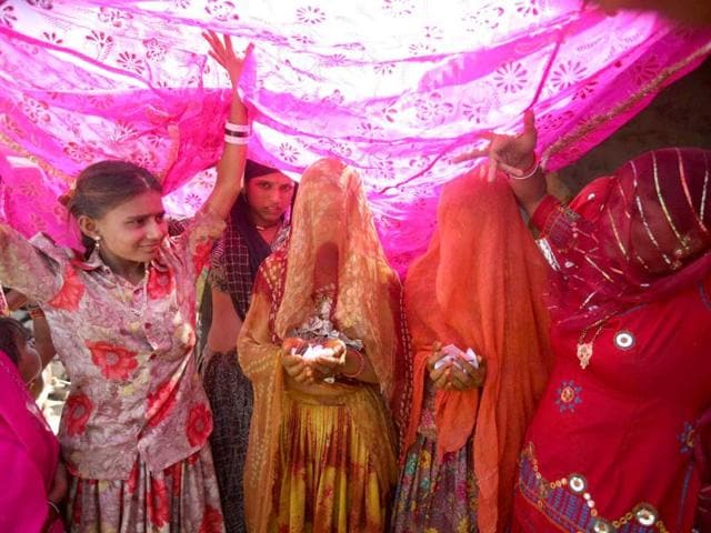Brides from the Saraniya community with their faces covered, walk towards the venue for rituals on the eve of their wedding at Vadia village in Gujarat. Brides from the Saraniya community with their faces covered, walk towards the venue for rituals on the eve of their wedding at Vadia village in Gujarat.