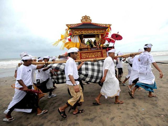 Balinese people carry an offering during the Melasti ceremony prayer at Petitenget beach in Kuta on the island of Bali. AFP Photo/Sonny Tumbelaka
