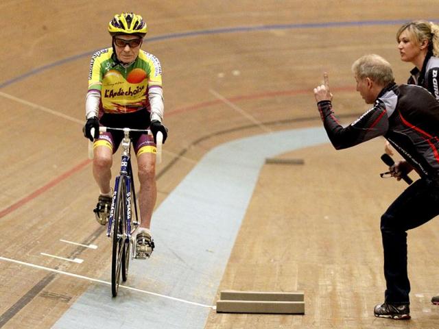 Trainer Robert Mistler (C) boosts cyclist Robert Marchand of France (L) next to trainer Magali Humbert-Perret during his attempt to set a world record for cycling non-stop for one hour, in the over 100- year old category, at the Union Cycliste Internationale (UCI) velodrome in Aigle on February 17, 2012. Reuters/Denis Balibouse