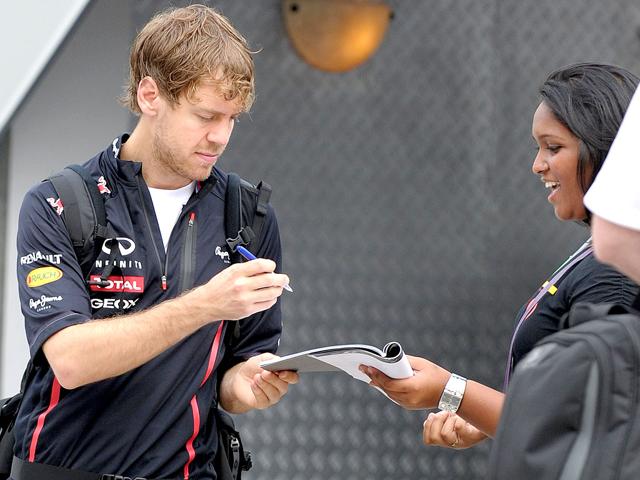 Red Bull-Renault driver Sebastian Vettel of Germany gives an autograph to a fan in the paddock area prior to the third practice session of Formula One Malaysian Grand Prix at the Sepang International Circuit in Sepang. AFP PHOTO / Prakash Singh